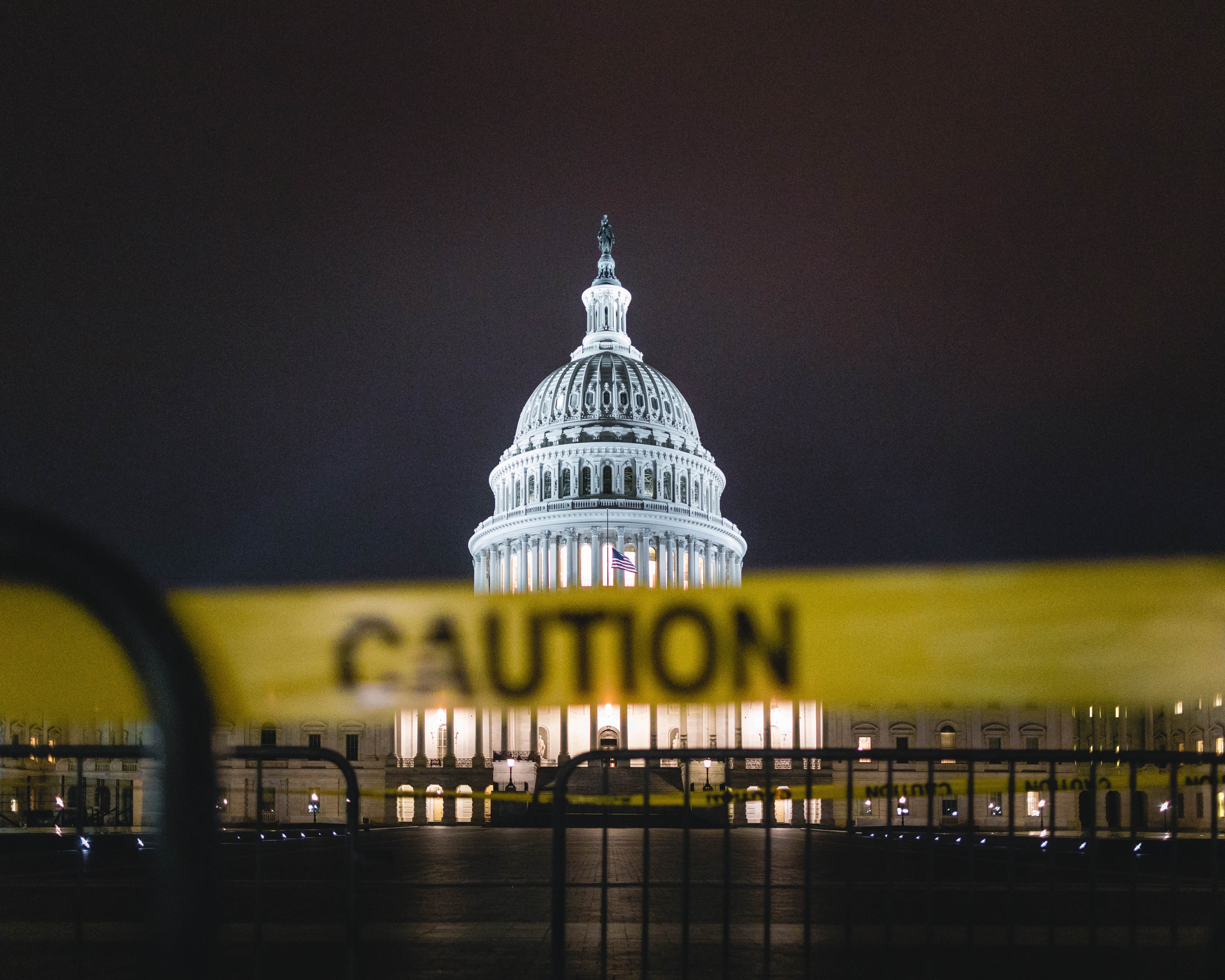 A caution tape perimeter surrounding the US Capitol at night time